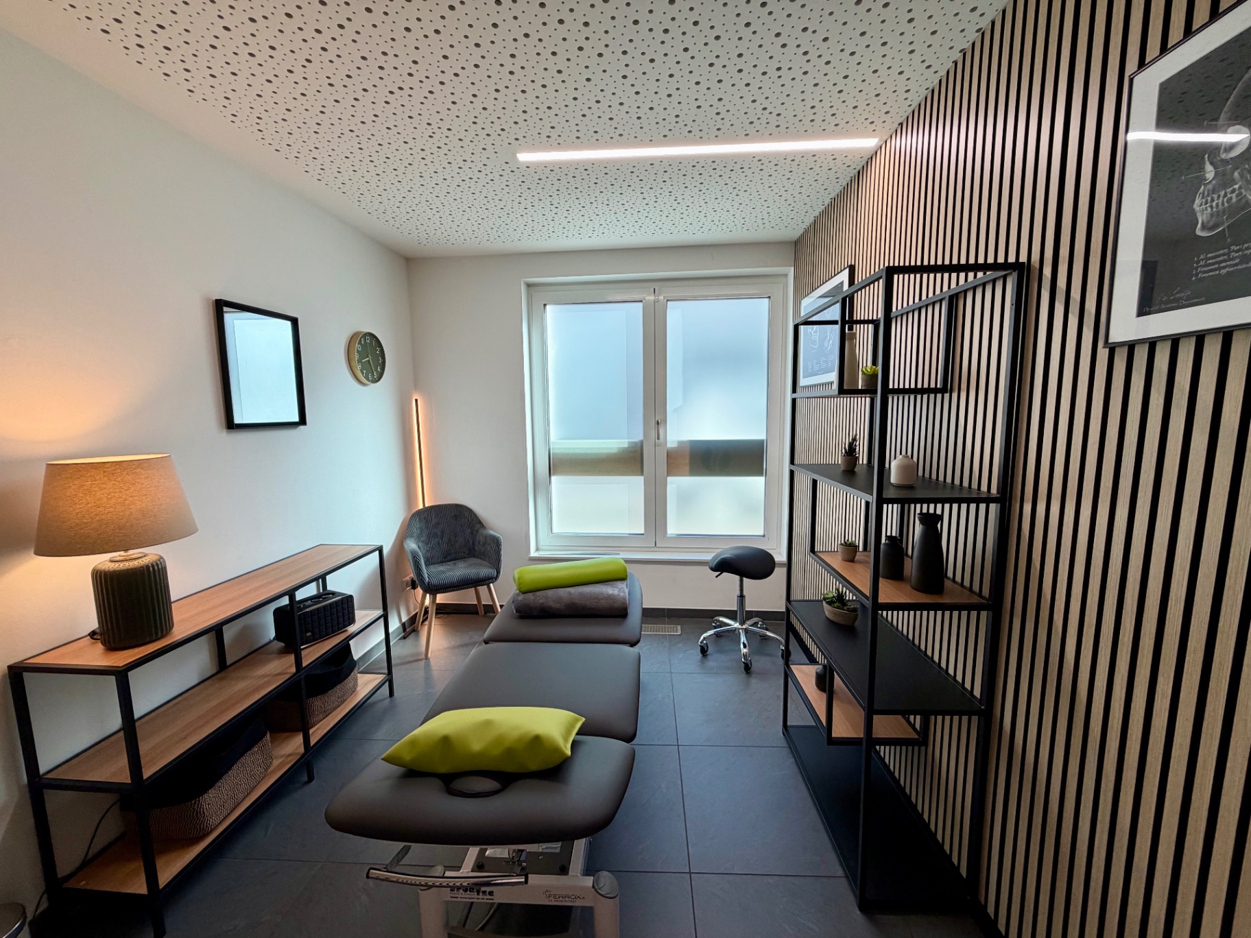 Heller Behandlungsraum mit Sideboard, Sessel und Therapieliege